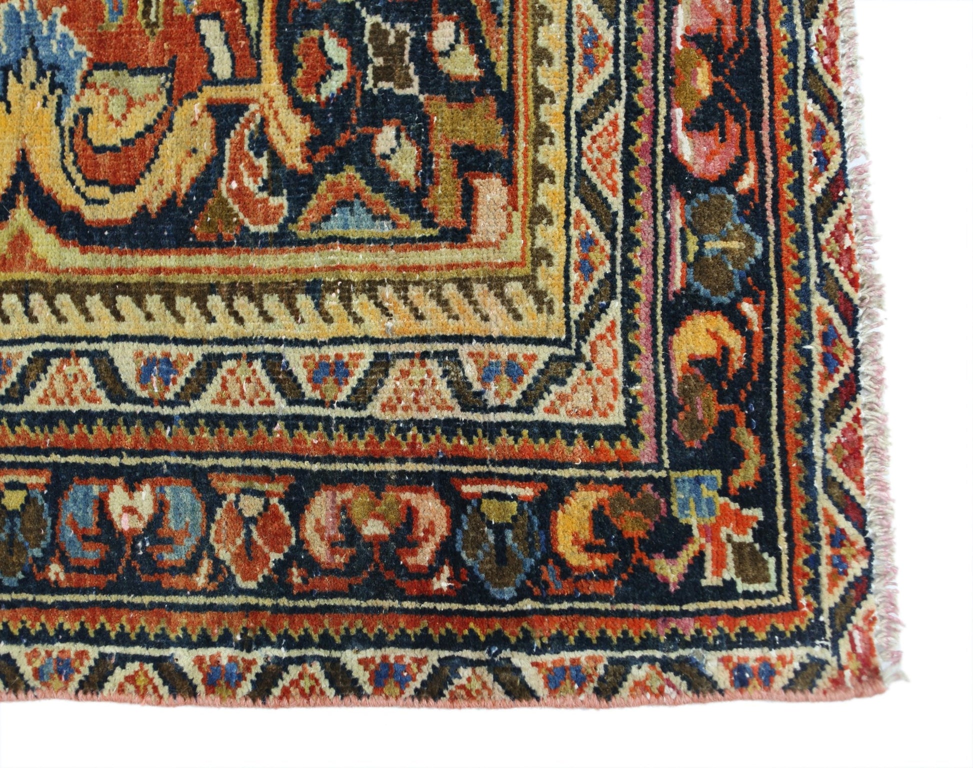A corner view of a vintage Persian Heriz rug featuring intricate geometric patterns in wool.