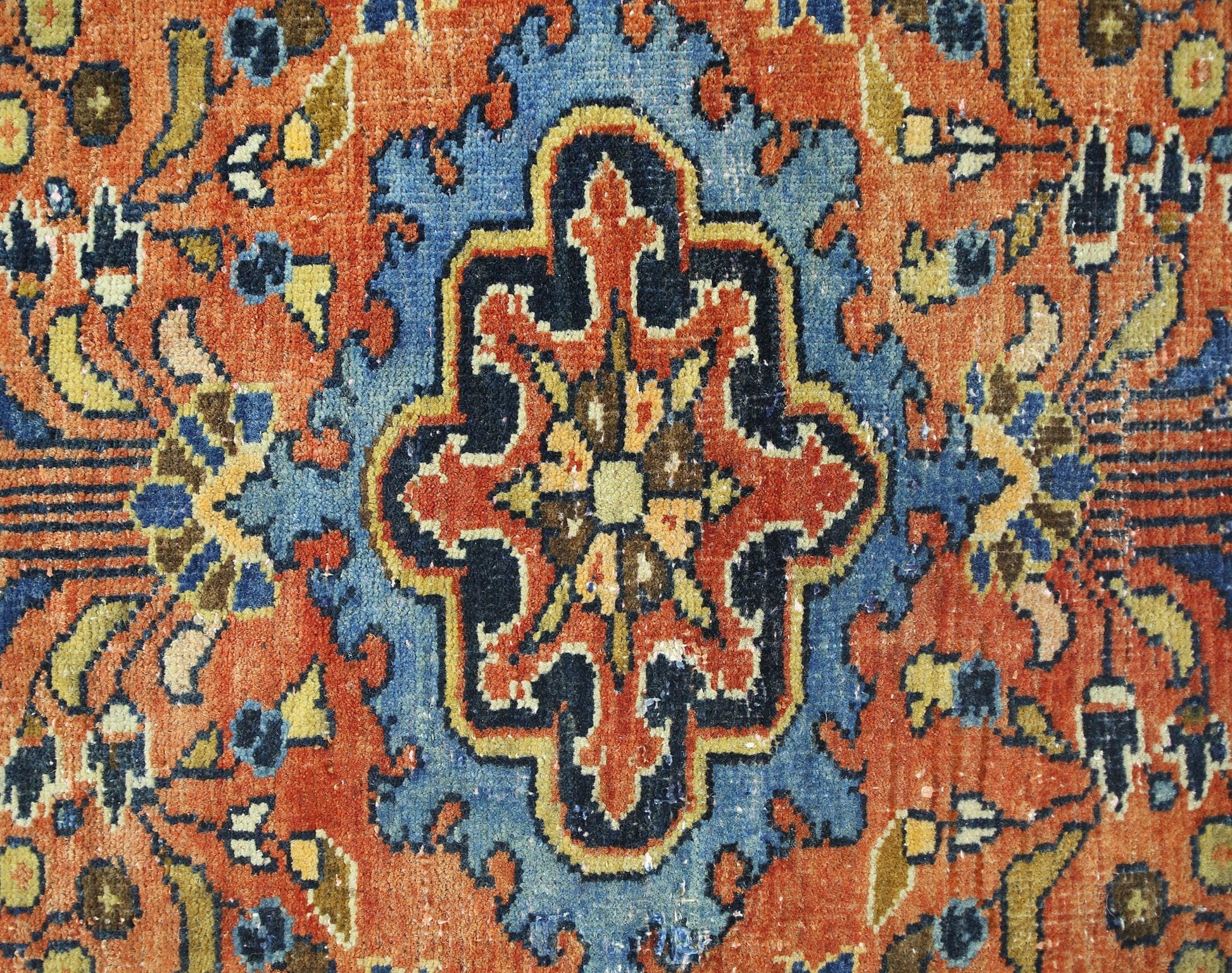 A vintage Persian Heriz rug featuring a central geometric medallion in blue, orange, and yellow.