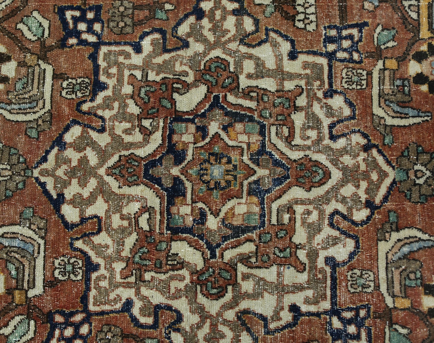 A vintage Persian Heriz rug featuring a geometric central medallion in rust, blue, and cream tones.