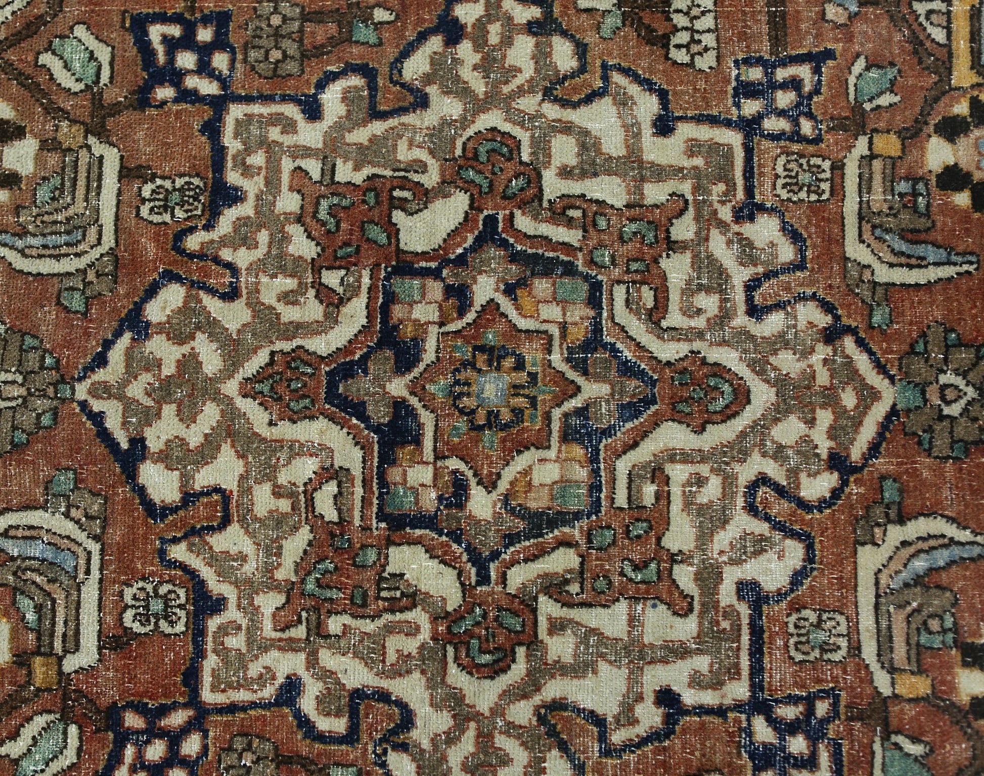 A vintage Persian Heriz rug featuring a geometric central medallion in rust, blue, and cream tones.