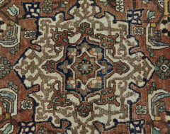 A vintage Persian Heriz rug featuring a geometric central medallion in rust, blue, and cream tones.