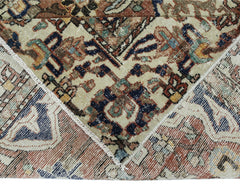 A vintage Persian Heriz rug with a folded corner showing its intricate geometric pattern.