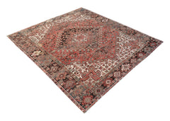 A vintage handwoven Persian Heriz rug featuring a geometric medallion pattern in red and blue tones.