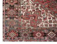 A vintage Persian Heriz rug featuring a geometric pattern in shades of red, cream, and dark grey.