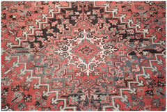 A vintage Persian Heriz rug featuring a geometric medallion pattern in red, black, and cream.
