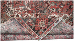 A vintage handwoven Persian Heriz rug featuring a geometric pattern in red, grey, and cream tones.