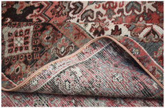A vintage handwoven Persian Heriz rug featuring a traditional geometric pattern in red and grey.