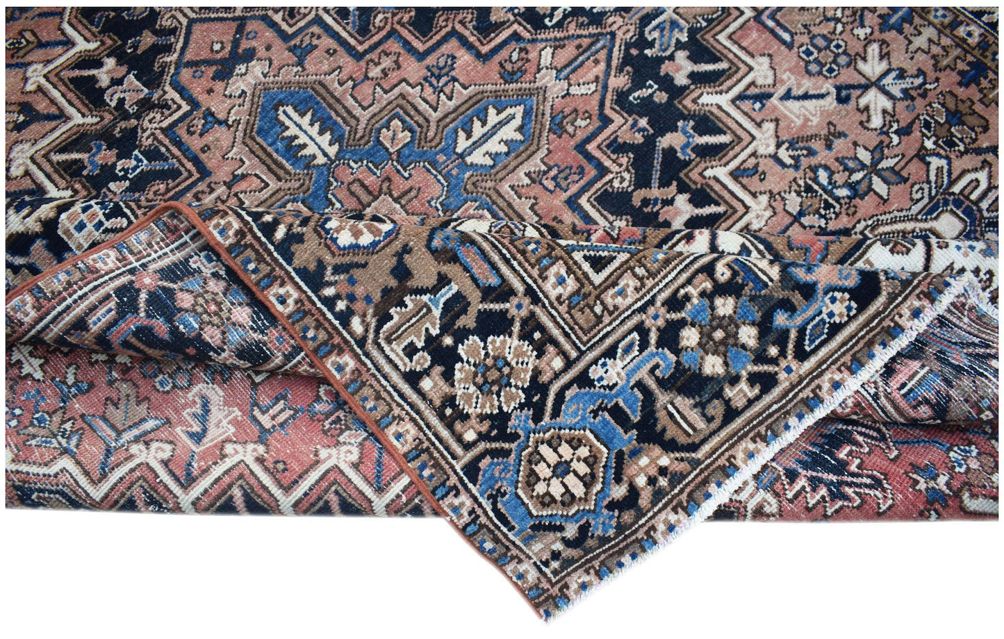 A vintage handwoven Persian Heriz rug featuring a geometric floral pattern in blue and pink tones.