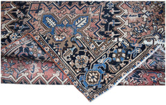 A vintage handwoven Persian Heriz rug featuring a geometric floral pattern in blue and pink tones.