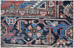 A close-up of a vintage Persian Heriz rug featuring intricate geometric patterns in red and blue.