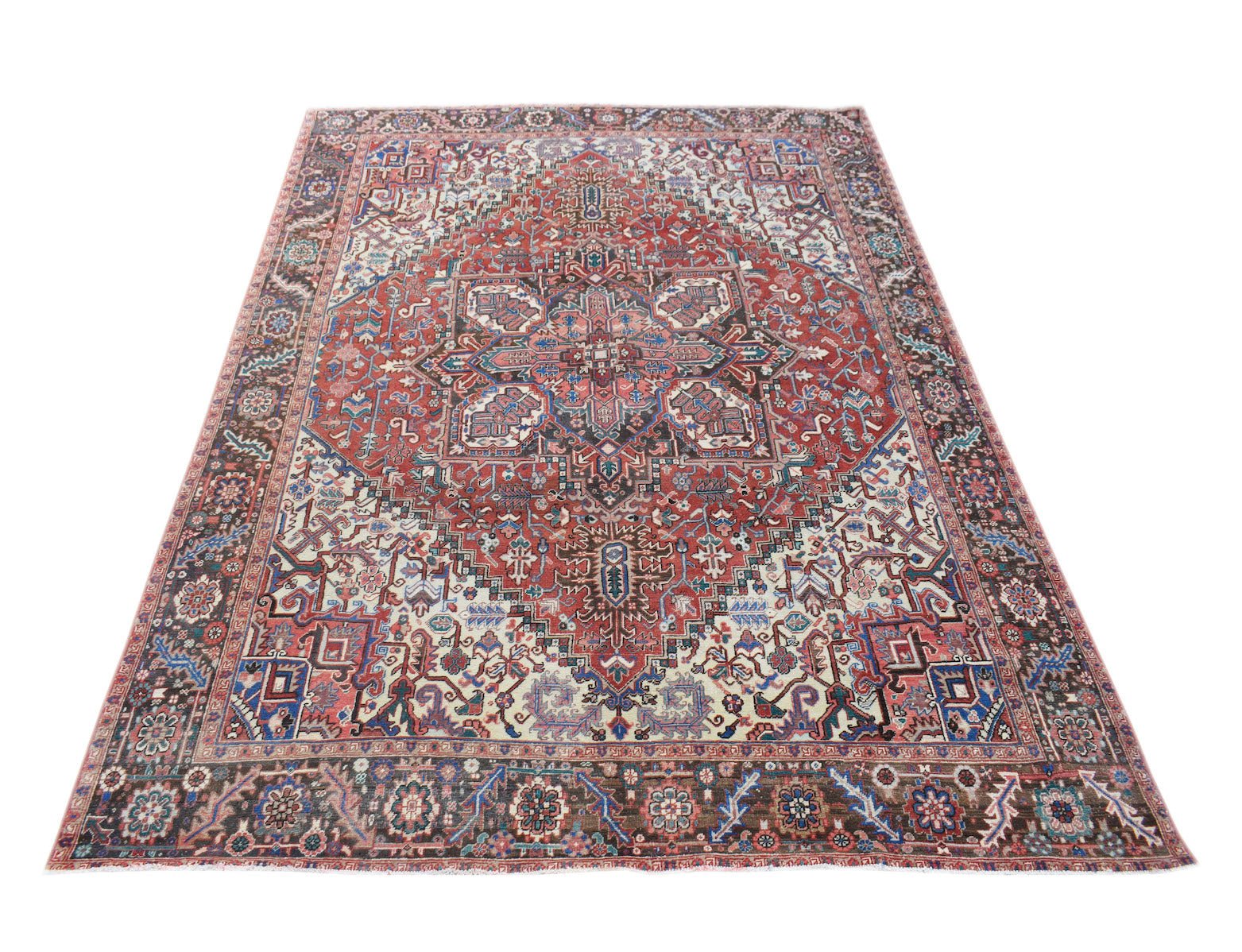 A vintage handwoven Persian Heriz rug featuring a geometric medallion on a red field.