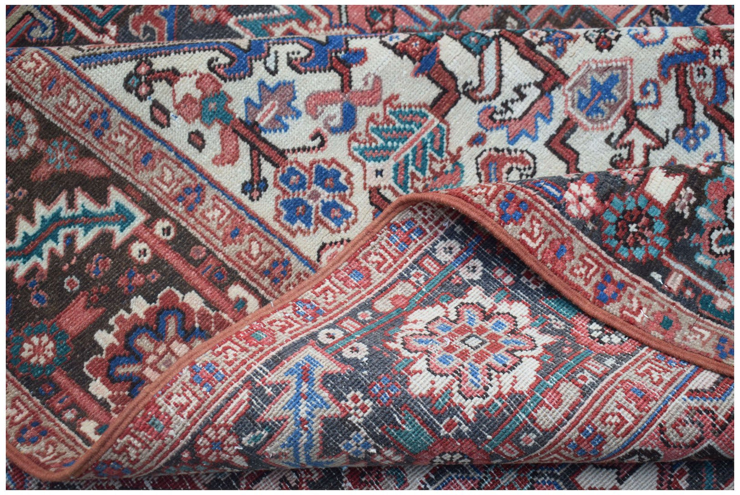 A handwoven vintage Persian Heriz rug featuring intricate floral patterns in red, blue, and cream.
