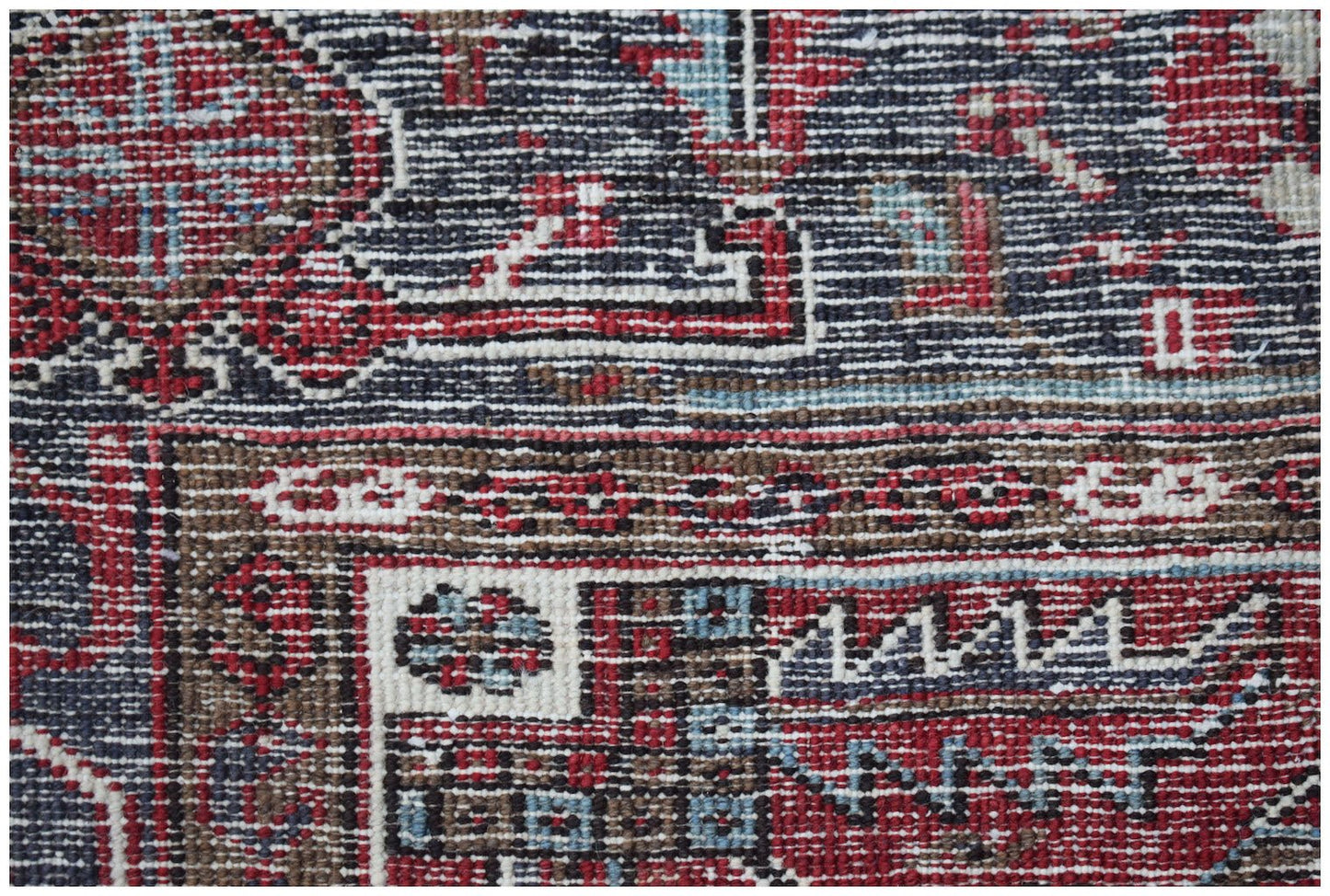 A close-up of a vintage Persian Heriz rug featuring intricate geometric patterns in red and blue.