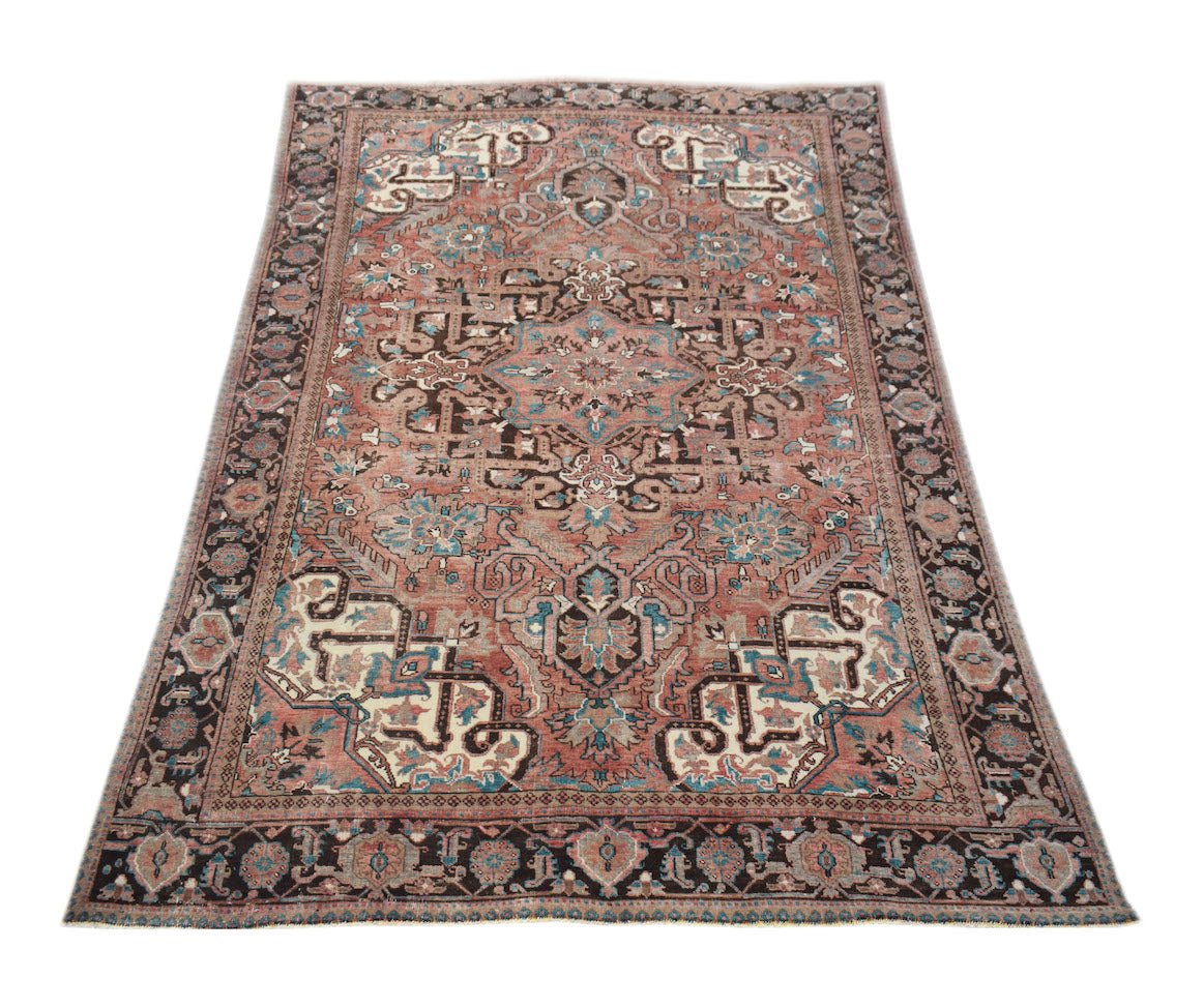 A vintage handwoven Persian Heriz rug featuring a geometric floral pattern in red and blue tones.