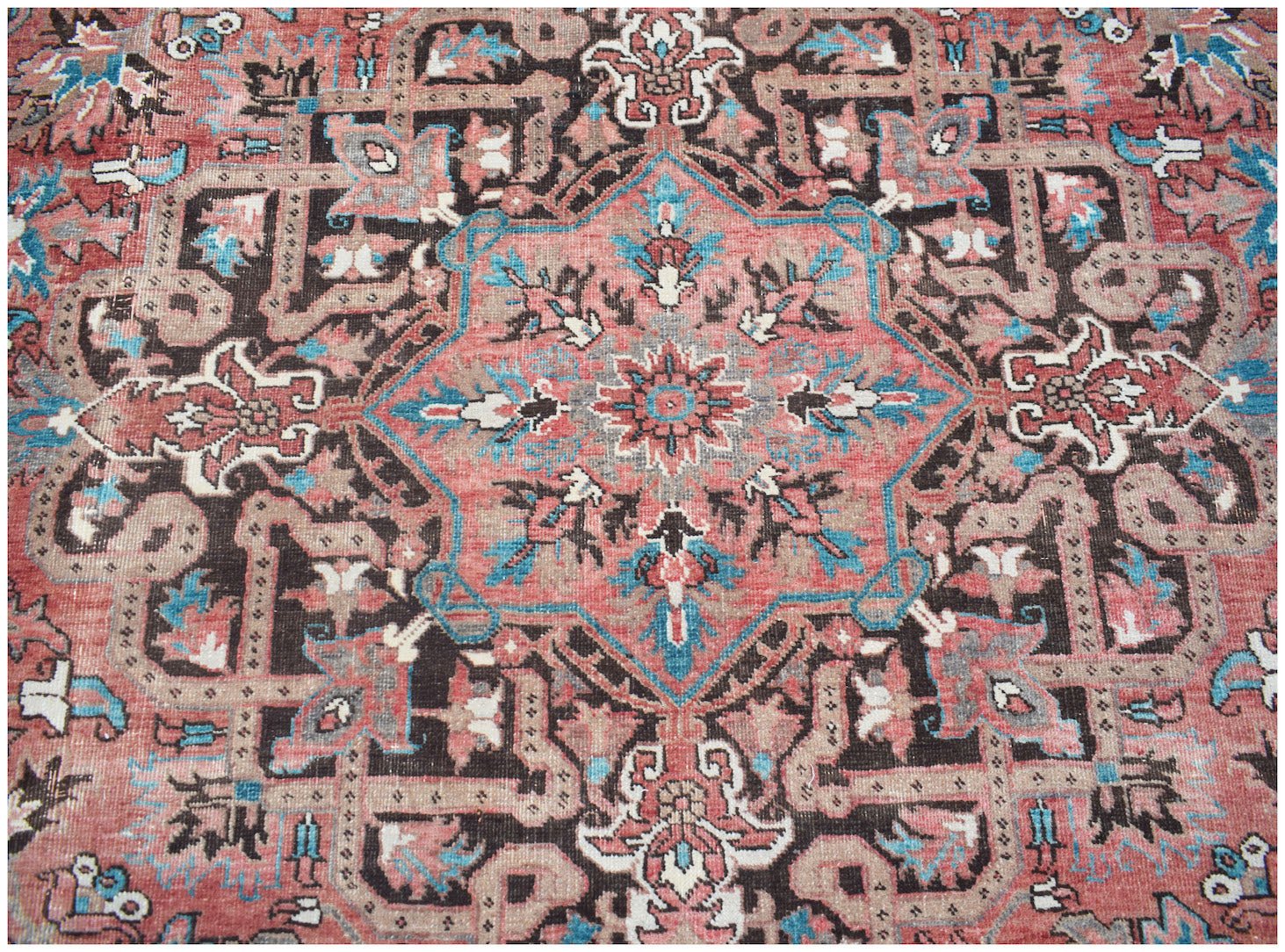 A vintage Persian Heriz rug featuring a geometric medallion in shades of red, blue, and brown.