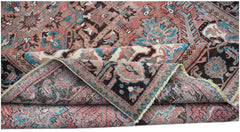 A vintage handwoven Persian Heriz rug featuring a geometric floral pattern in red, blue, and brown.