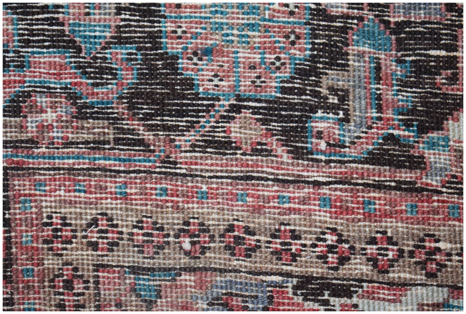 A close-up view of a vintage Persian Heriz rug featuring intricate geometric patterns in wool.