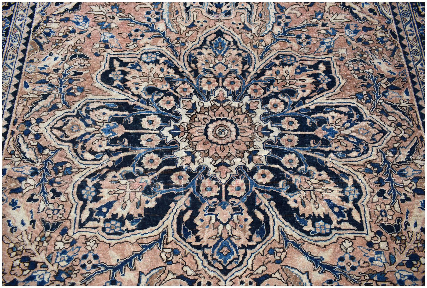 A vintage handwoven Persian Heriz rug featuring a large central floral medallion in blue and pink.