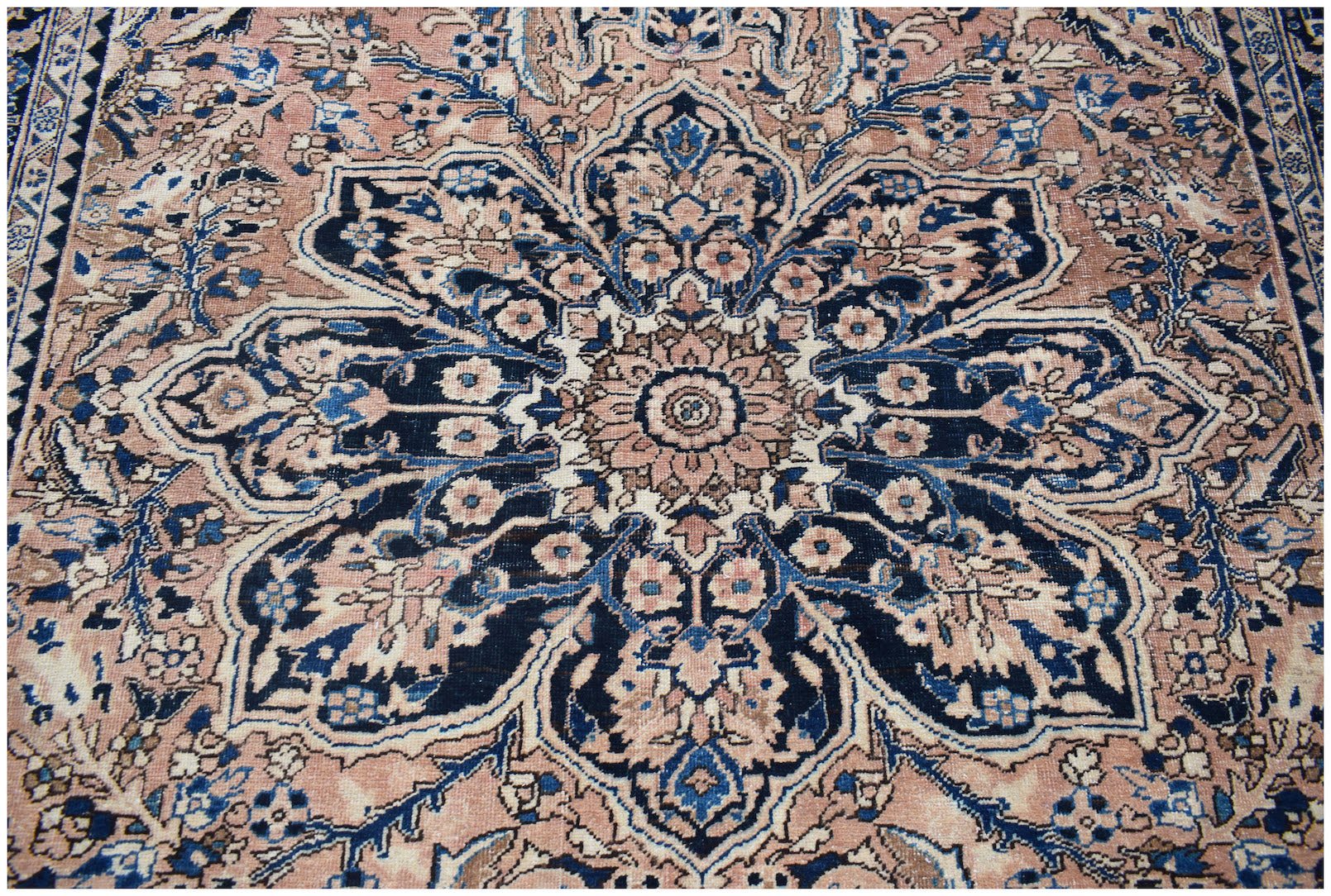 A vintage handwoven Persian Heriz rug featuring a large central floral medallion in blue and pink.