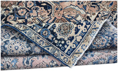 A vintage handwoven Persian Heriz rug featuring a traditional floral pattern in blue and pink tones.