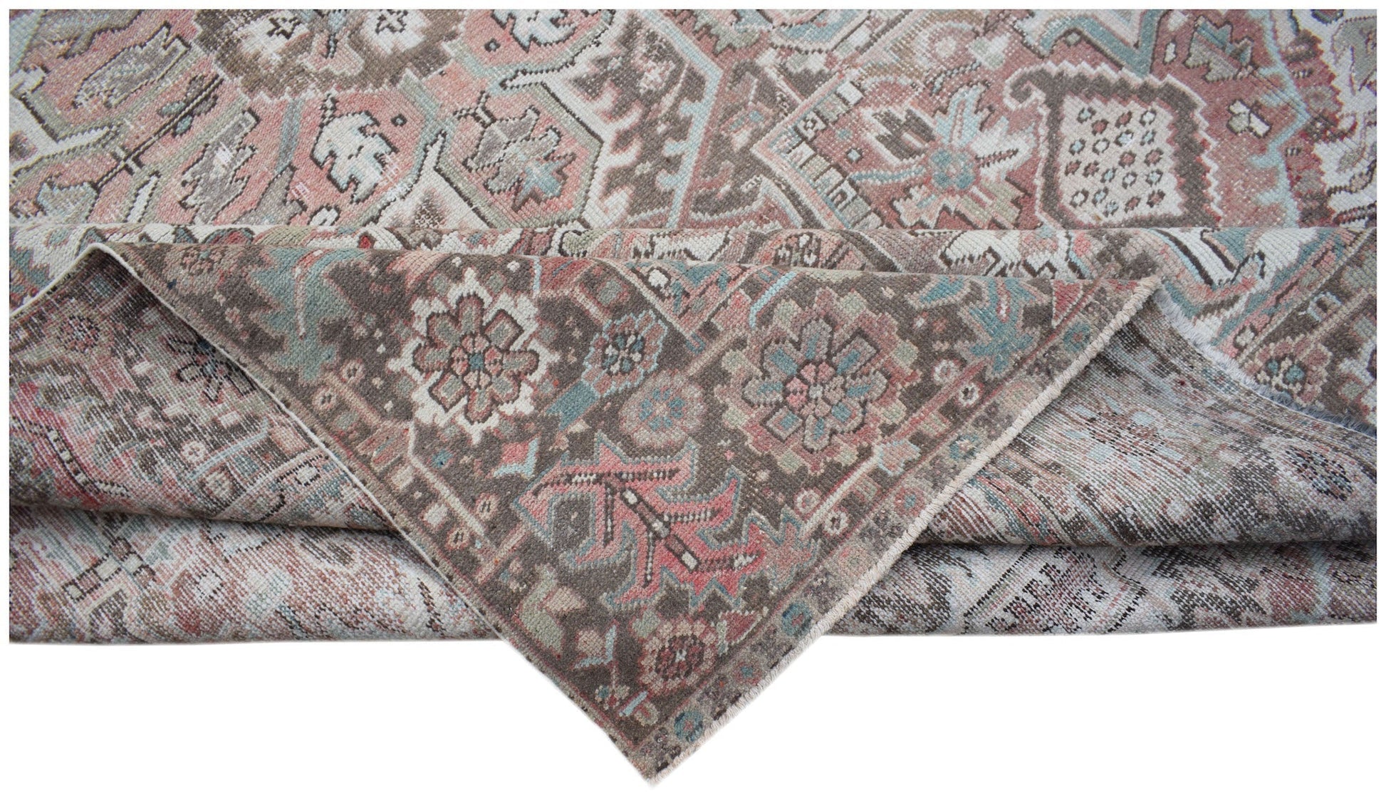 A vintage Persian Heriz rug featuring a faded floral pattern in muted pink, blue, and brown tones.