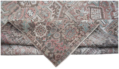 A vintage Persian Heriz rug featuring a faded floral pattern in muted pink, blue, and brown tones.