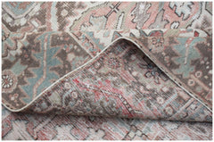 A vintage Persian Heriz rug with a faded floral pattern in muted pink, blue, and brown tones.