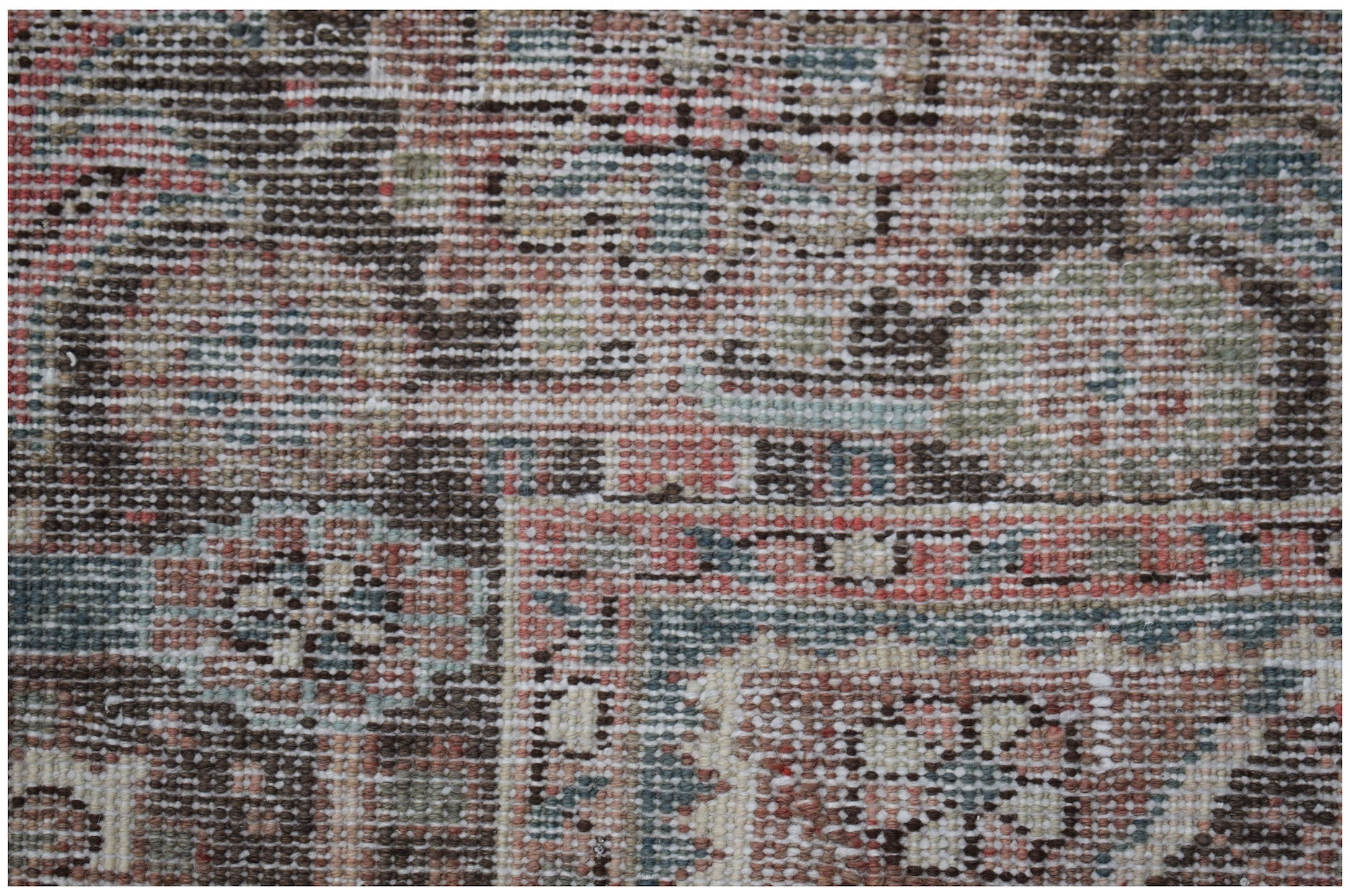 A close-up of a vintage Persian Heriz rug featuring a geometric pattern in muted earth tones.