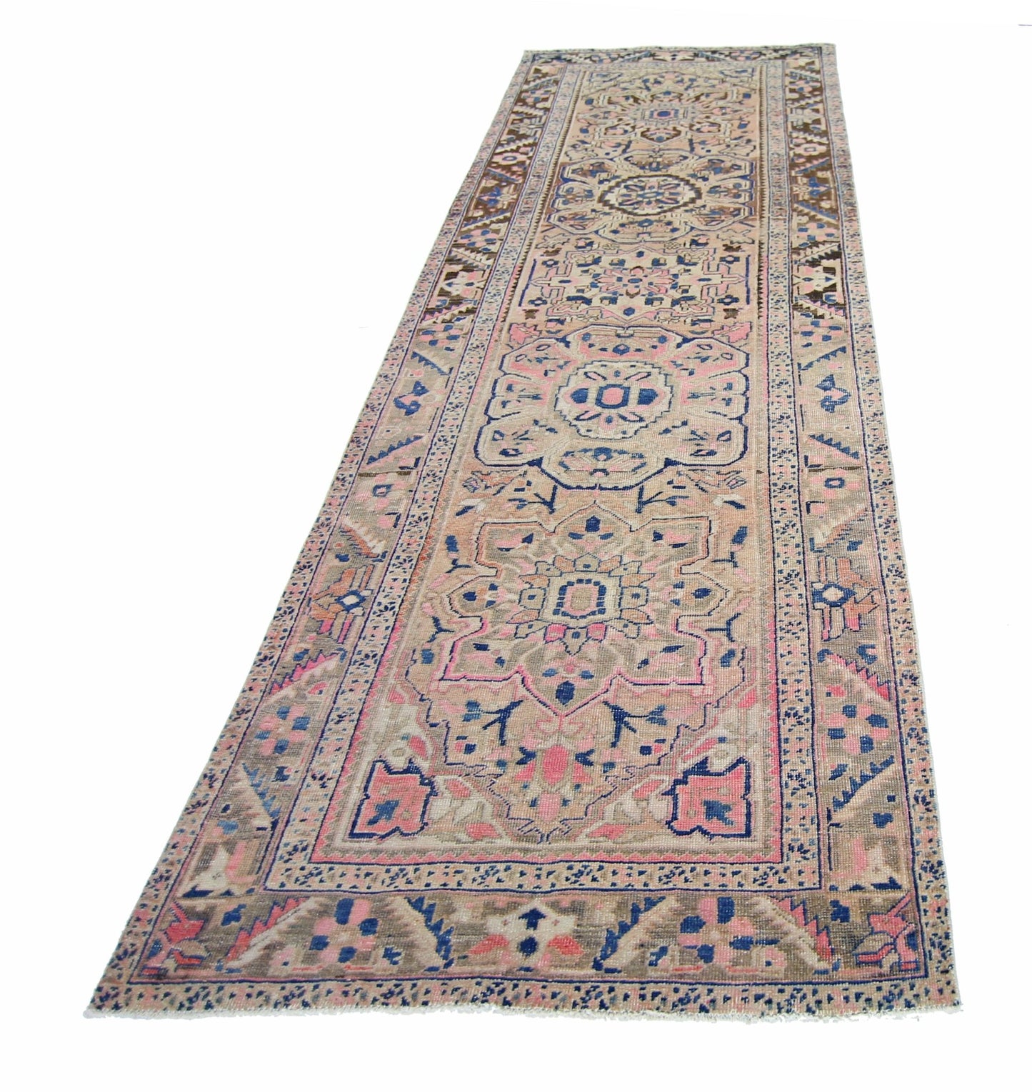 A vintage Persian Heriz runner rug featuring geometric floral patterns in pink, blue, and beige.