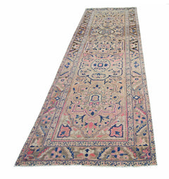 A vintage Persian Heriz runner rug featuring geometric floral patterns in pink, blue, and beige.