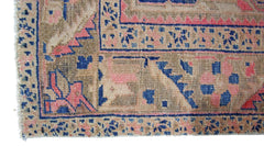 A vintage Persian Heriz runner featuring a geometric pattern in faded blue, pink, and tan tones.