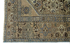 A vintage handmade Persian rug featuring intricate geometric patterns in blue and brown tones.