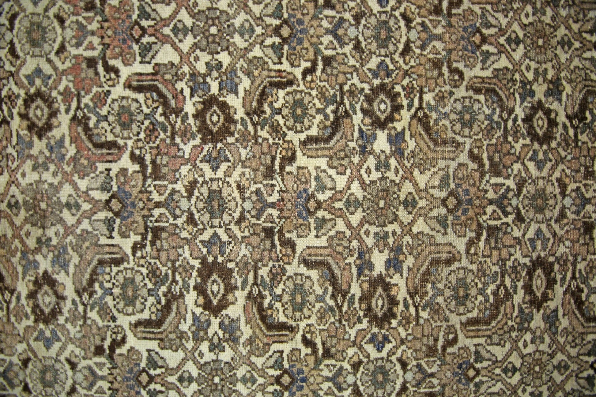 A vintage Persian rug featuring an intricate, repeating floral pattern in muted earth tones.