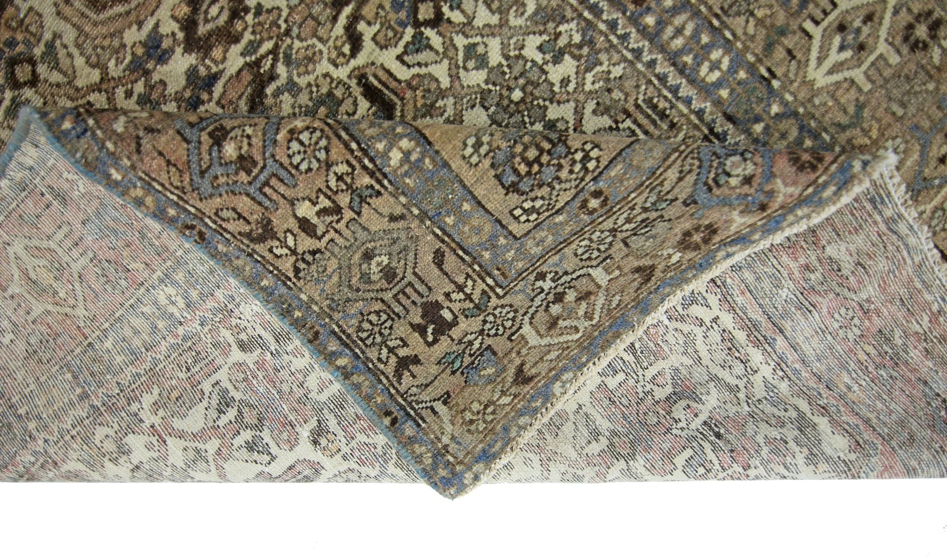 A vintage handmade Persian rug with intricate geometric patterns in muted blue and brown tones.