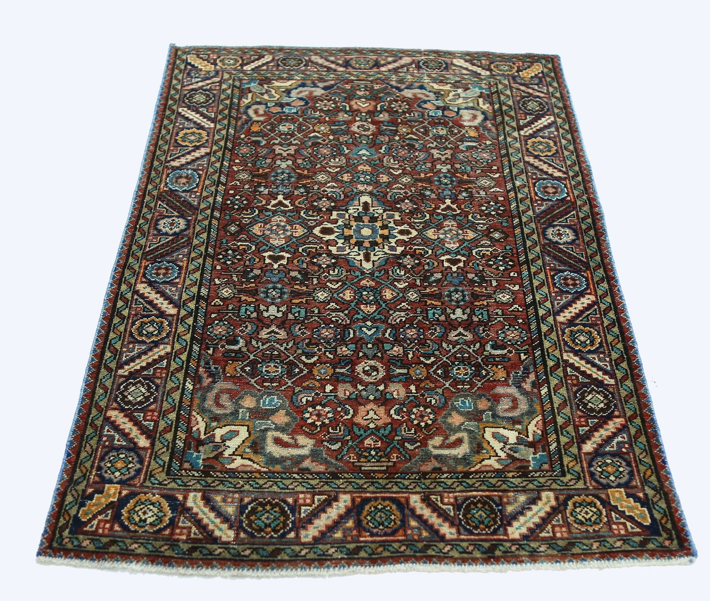 A rectangular vintage Persian rug featuring a detailed floral pattern in red, blue, and cream tones.