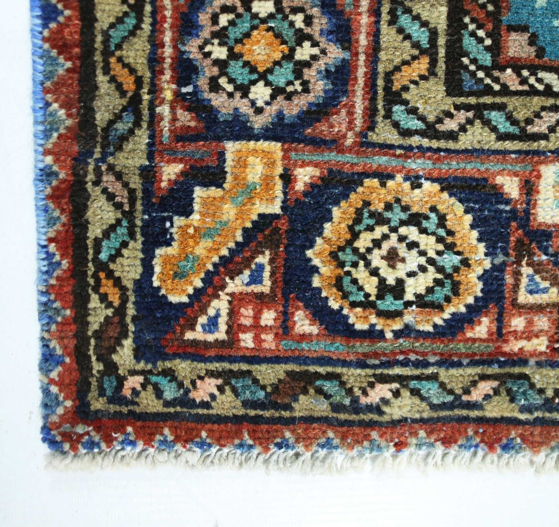 A corner view of a vintage handmade Persian rug featuring intricate geometric patterns in wool.