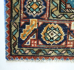 A corner view of a vintage handmade Persian rug featuring intricate geometric patterns in wool.