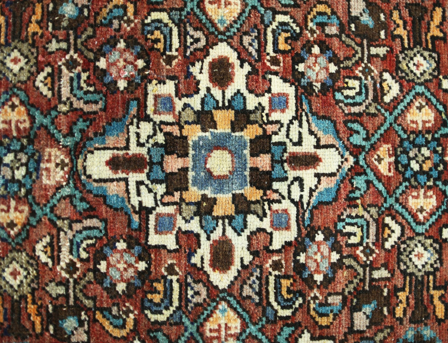 A vintage Persian rug featuring a detailed geometric medallion pattern in red, blue, and cream.