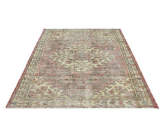 A vintage handmade Persian rug featuring a traditional floral medallion pattern in faded red tones.
