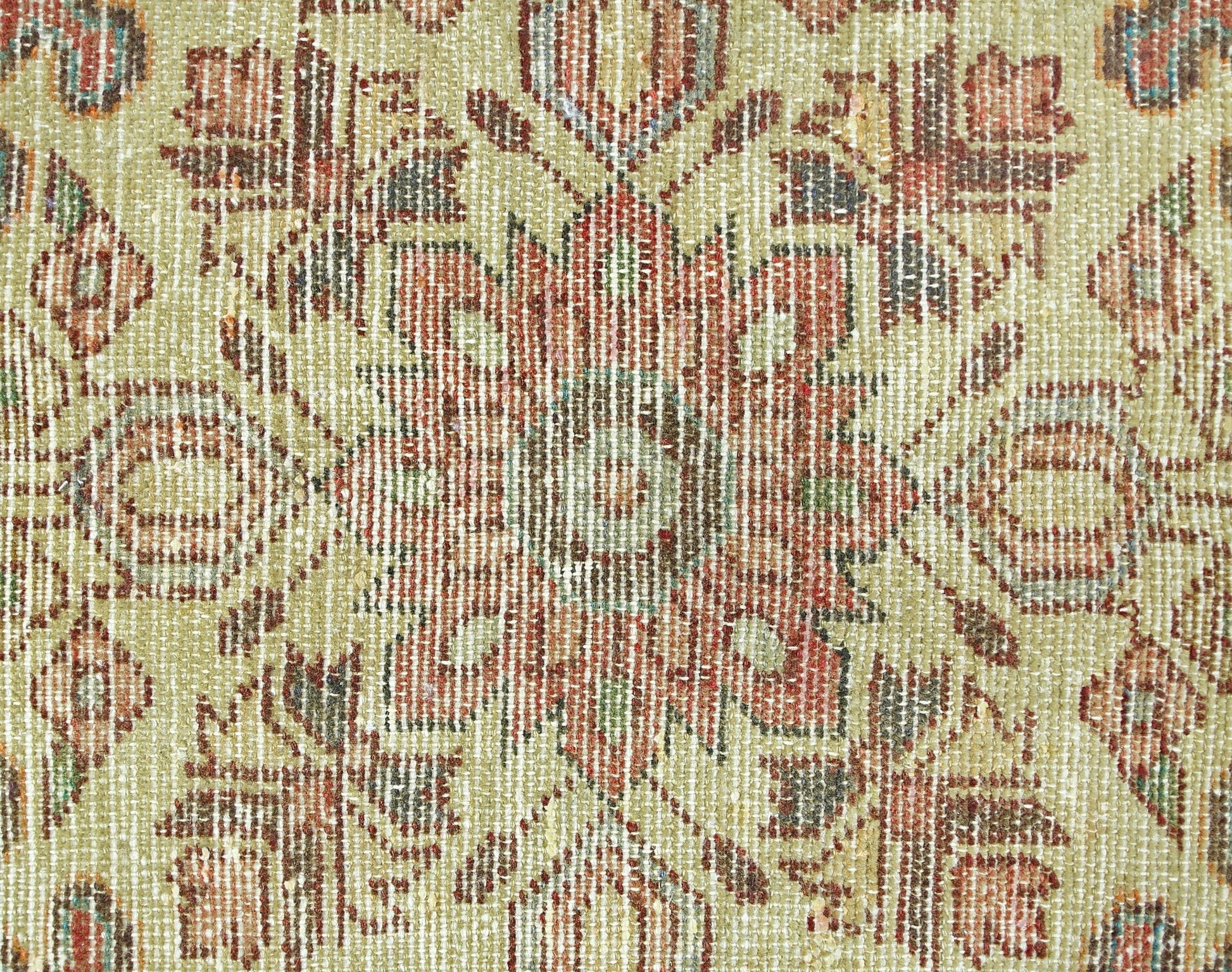 A close-up of a vintage Persian rug featuring a detailed floral medallion in muted earth tones.