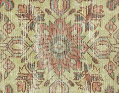 A close-up of a vintage Persian rug featuring a detailed floral medallion in muted earth tones.