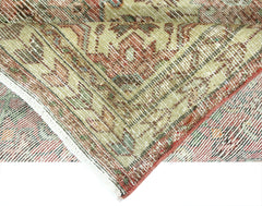 A folded vintage Persian rug featuring intricate floral patterns in muted red and green tones.