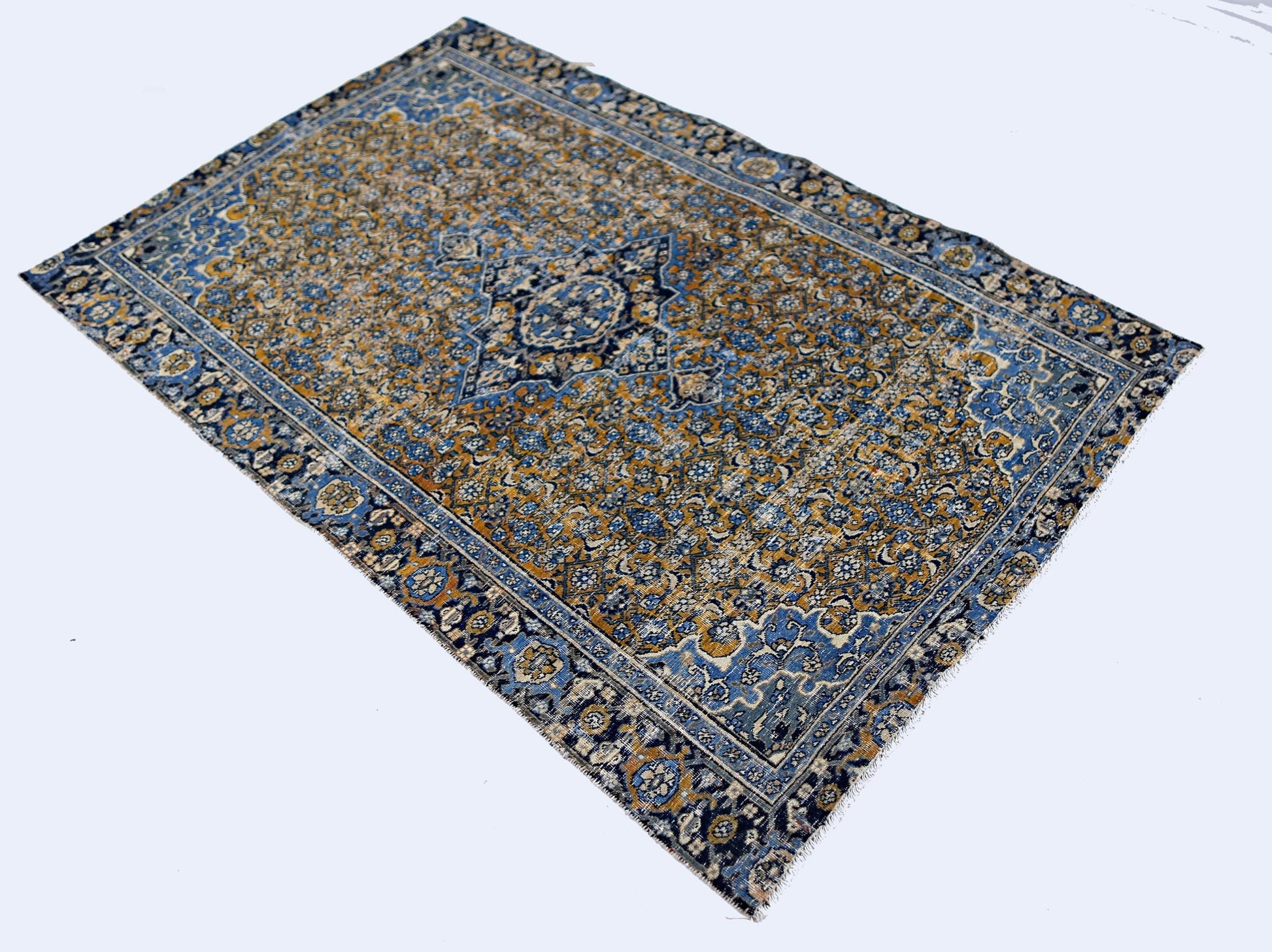 A vintage Persian Hossainabad rug featuring a blue and gold floral pattern on a wool pile.