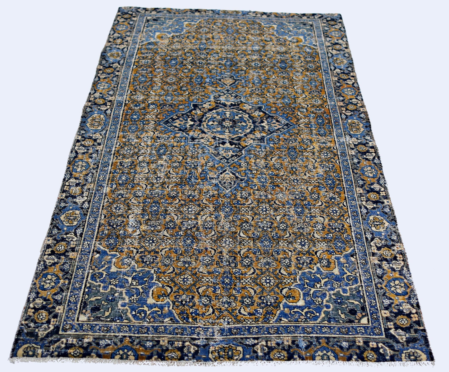A vintage handmade Persian Hossainabad rug featuring an intricate blue and gold floral pattern.