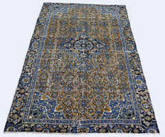 A vintage handmade Persian Hossainabad rug featuring an intricate blue and gold floral pattern.