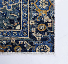A vintage Persian Hossainabad rug featuring intricate floral patterns in blue, gold, and cream.