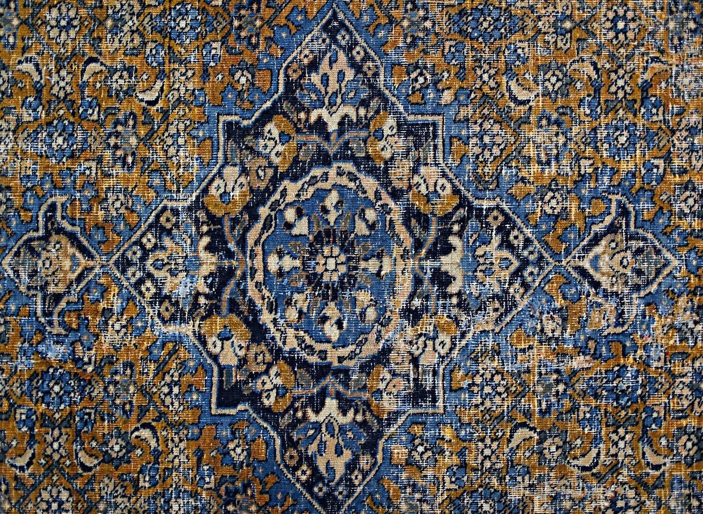 A vintage Persian Hossainabad rug featuring a central medallion in blue, gold, and cream tones.