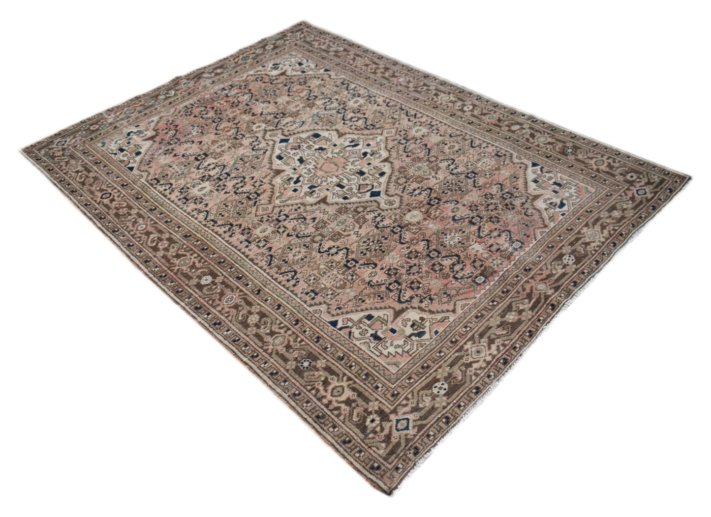 A handwoven vintage Persian rug featuring a faded floral pattern in muted pink and brown tones.