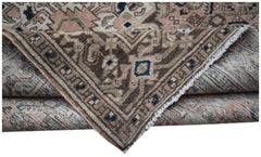 A handwoven vintage Persian rug featuring a faded floral pattern in muted earth tones.