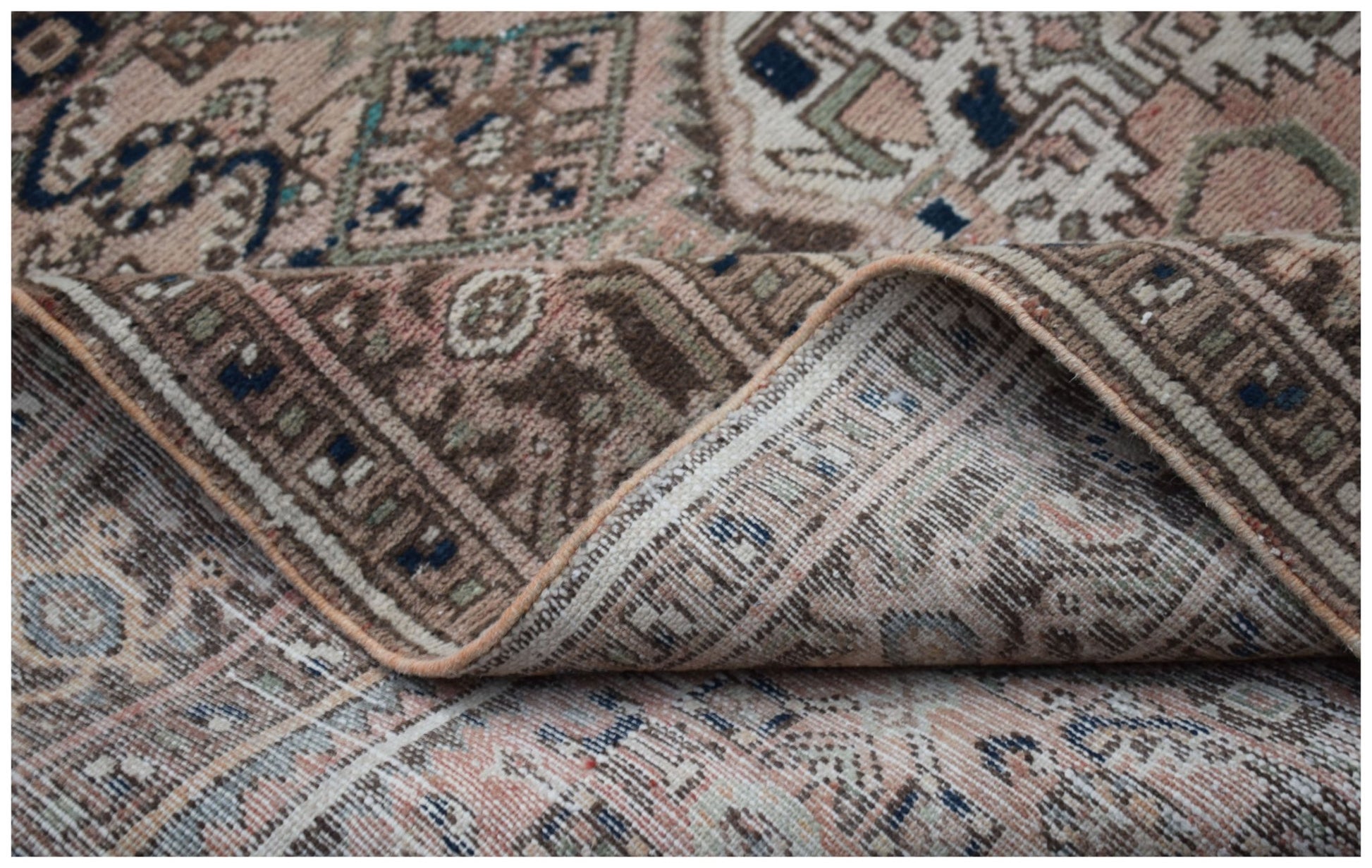 A handwoven vintage Persian rug featuring intricate geometric patterns in muted earth tones.